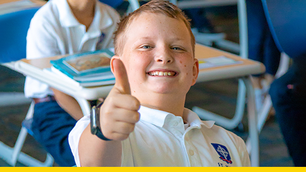 Little boy smiling and giving a thumbs up to the camera